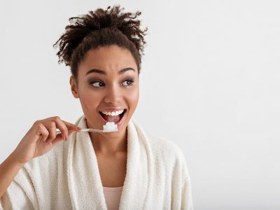 Woman with beautiful teeth brushing with old school toothbrush