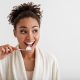 Woman with beautiful teeth brushing with old school toothbrush